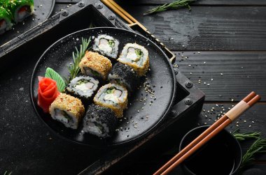 Geleneksel suşi - Siyah ve beyaz, yengeç, peynir ve bitkilerle. Japon mutfağı. Üst görünüm.