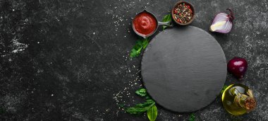 Pişirme afişi. Siyah bir arka plan üzerinde sebze ve baharatlar. Metniniz için boş alan. Rustik stil.