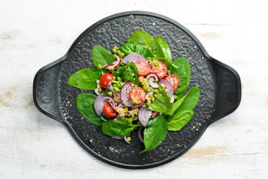 Ispanak, kinoa, domates ve sebzeden oluşan sağlıklı bir vegan salatası. Üst Manzara. Kırsal biçim.