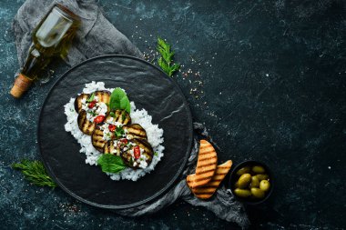 Siyah tabakta pilav ve peynirle kızartılmış patlıcan. Üst Manzara. Kırsal biçim.