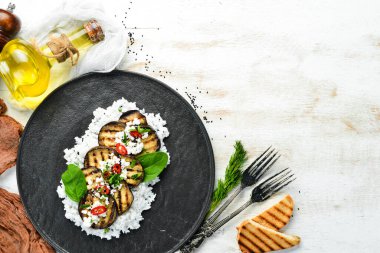 Siyah tabakta pilav ve peynirle kızartılmış patlıcan. Üst Manzara. Kırsal biçim.