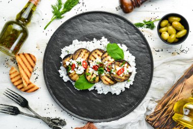 Siyah tabakta pilav ve peynirle kızartılmış patlıcan. Üst Manzara. Kırsal biçim.