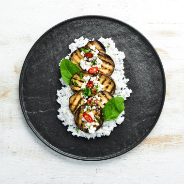 Siyah tabakta pilav ve peynirle kızartılmış patlıcan. Üst Manzara. Kırsal biçim.