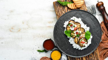 Siyah tabakta pilav ve peynirle kızartılmış patlıcan. Üst Manzara. Kırsal biçim.