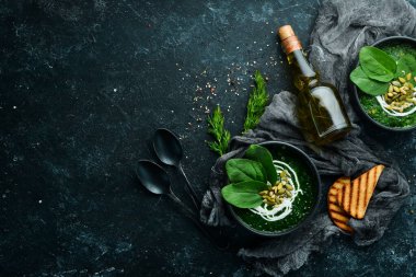 Kremalı yeşil ıspanak kremalı çorba ve kabak çekirdekli siyah kase. Sağlıklı yiyecekler. Üst Manzara. Kırsal biçim.