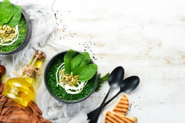 Kremalı yeşil ıspanak kremalı çorba ve kabak çekirdekli siyah kase. Sağlıklı yiyecekler. Üst Manzara. Kırsal biçim.