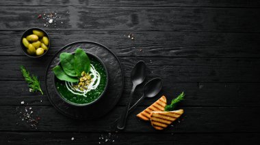 Kremalı yeşil ıspanak kremalı çorba ve kabak çekirdekli siyah kase. Sağlıklı yiyecekler. Üst Manzara. Kırsal biçim.