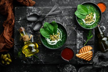 Kremalı yeşil ıspanak kremalı çorba ve kabak çekirdekli siyah kase. Sağlıklı yiyecekler. Üst Manzara. Kırsal biçim.