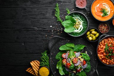 Renkli çorba seti. Ispanak çorbası, domates kremalı çorba ve havuç püresi çorbası. Sağlıklı yiyecekler. Siyah taştan bir arka planda.