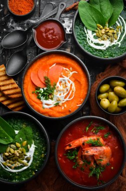 Renkli çorba seti. Ispanak çorbası, domates kremalı çorba ve havuç püresi çorbası. Sağlıklı yiyecekler. Siyah taştan bir arka planda.