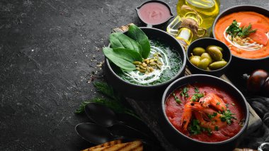 Üç kase ve renkli çorba. Ispanak, domates ve havuç çorbası. Sağlıklı yiyecekler. Karanlık bir arka planda.