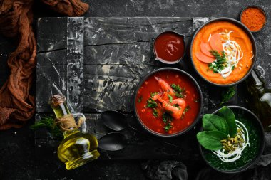 Üç kase ve renkli çorba. Ispanak, domates ve havuç çorbası. Sağlıklı yiyecekler. Karanlık bir arka planda.