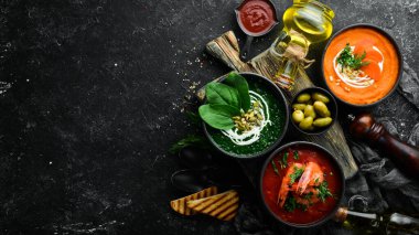 Üç kase ve renkli çorba. Ispanak, domates ve havuç çorbası. Sağlıklı yiyecekler. Karanlık bir arka planda.