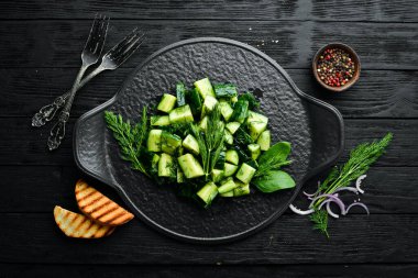 Salatalıklı vejetaryen salatası ve siyah tabakta dereotu. Kırsal tarzda. Üst Manzara. Metnin için boş yer.