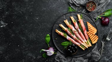 İtalyan Antipasto. Siyah tabakta jambonlu Grissini ekmeği. Kırsal tarzda. Üst Manzara. Metnin için boş yer.