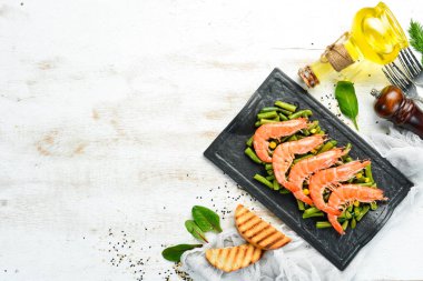 Siyah taş tabakta haşlanmış karides ve yeşil fasulye. Kırsal tarzda. Üst Manzara. Metnin için boş yer.