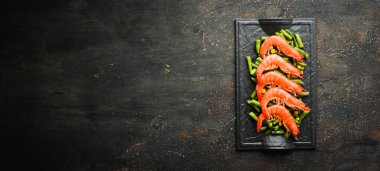 Siyah taş tabakta haşlanmış karides ve yeşil fasulye. Kırsal tarzda. Üst Manzara. Metnin için boş yer.