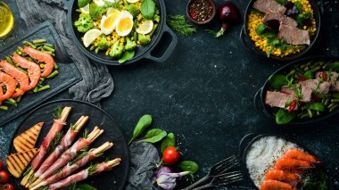 Yiyecekler. Tabakları siyah masaya koyun. Et ve deniz ürünleri tabakları. Kırsal biçim.