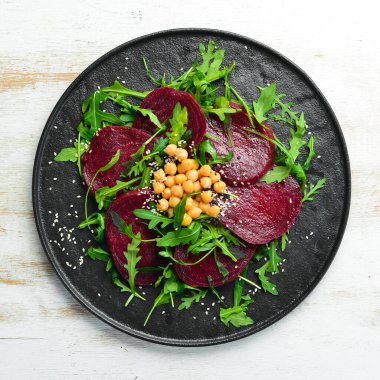 Vejetaryen salatası: siyah bir tabakta pancar, roka ve nohut. Sağlıklı diyet yemekleri. Üst Manzara. Metin için boş alan.
