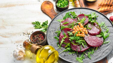 Vejetaryen salatası: siyah bir tabakta pancar, roka ve nohut. Sağlıklı diyet yemekleri. Üst Manzara. Metin için boş alan.