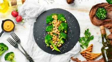Sağlıklı yiyecekler: ızgara brokoli, nohut ve siyah taş tabakta susam. Üst Manzara. Metin için boş alan.