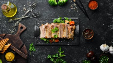Siyah taş tabakta fırında domuz pirzolası, hardal ve baharat. Üst Manzara. Metin için boş alan.