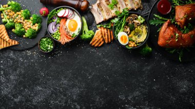 Yemek: makarna, domuz pirzolası, avokado, Buda kasesi ve siyah taş zemin üzerinde pancar salatası. Üst Manzara. Metin için boş alan.