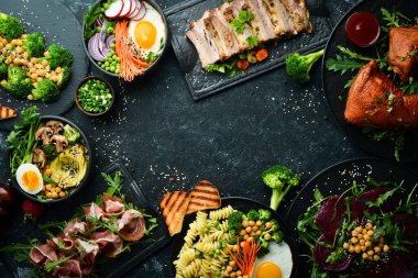 Yemek: makarna, domuz pirzolası, avokado, Buda kasesi ve siyah taş zemin üzerinde pancar salatası. Üst Manzara. Metin için boş alan.