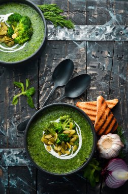 Siyah kasede yeşil kremalı brokoli çorbası ve kabak çekirdeği. Üst Manzara. Metnin için boş yer. Kırsal biçim.