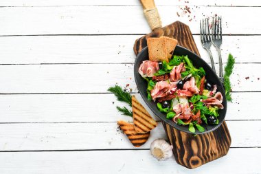 Siyah kasede zeytinli jambonlu salata. İspanyol mutfağı. Üst Manzara. Metnin için boş yer. Kırsal biçim.