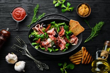 Siyah kasede zeytinli jambonlu salata. İspanyol mutfağı. Üst Manzara. Metnin için boş yer. Kırsal biçim.