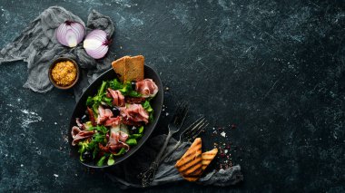 Siyah kasede zeytinli jambonlu salata. İspanyol mutfağı. Üst Manzara. Metnin için boş yer. Kırsal biçim.