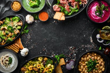 Restoran menüsü. Siyah taş arka planda yemek ve tabaklar. Üst görünüm.