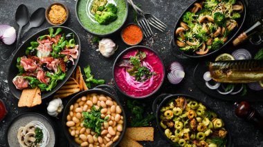 Restoran menüsü. Siyah taş arka planda yemek ve tabaklar. Üst görünüm.