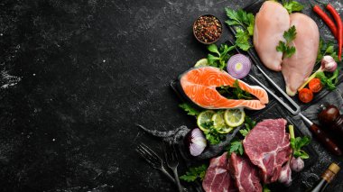 Et seti. Balık biftek, dana biftek ve tavuk göğsü. Üst Manzara. Siyah taştan bir arka planda.