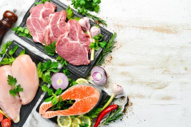 Çiğ et, dana eti, domuz eti ve balık. Üst Manzara. Beyaz ahşap bir arka planda. Metnin için boş yer.