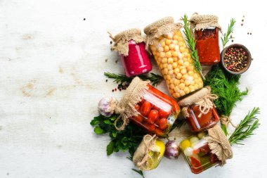 Beyaz ahşap arka planda cam kavanozlarda konserve yiyecekler. Sebze ve mantar turşusu..