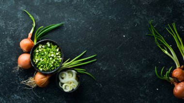 Taze taze taze taze taze soğan ve siyah taş zemin üzerinde taze doğranmış yeşil soğan. Üst görünüm.