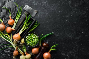 Taze taze taze taze taze soğan ve siyah taş zemin üzerinde taze doğranmış yeşil soğan. Üst görünüm.