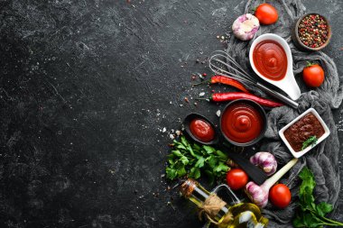 Domatesli ketçap sosu. Acı kırmızı sos. Siyah taştan bir arka planda.