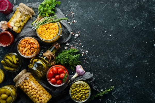 Cam kavanozlarda yiyecek stokları. Sebze turşusu. Siyah bir arka planda. Üst görünüm.