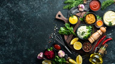 Siyah taş arka planda renkli soslar ve baharatlar. Et ve balık için geleneksel soslar.