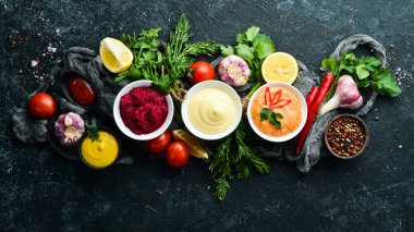 Siyah taş arka planda renkli soslar ve baharatlar. Et ve balık için geleneksel soslar.