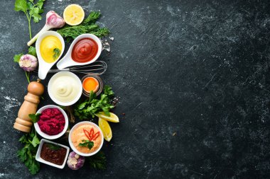 Siyah taş arka planda renkli soslar ve baharatlar. Et ve balık için geleneksel soslar.