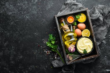 Mayonez sosu ve siyah taş zemin üzerindeki malzemeler. Üst görünüm.