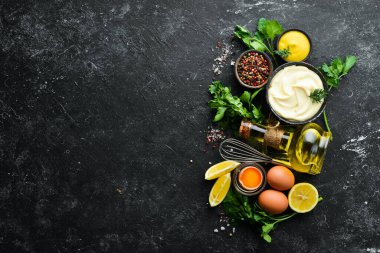 Mayonez sosu ve siyah taş zemin üzerindeki malzemeler. Üst görünüm.