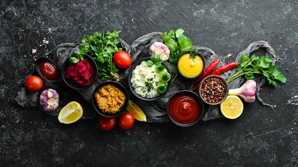 Siyah taş arka planda renkli soslar ve baharatlar. Et ve balık için geleneksel soslar.