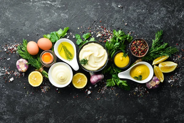 Mayonez sosu pişiriyorum. Yağ, hardal ve yumurta. Mutfak siyah taş arka planı. Üst görünüm.