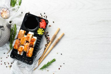 Lezzetli Japon suşisi, yılan balığı ve Philadelphia peynirli. Plastik kutularda yiyecek teslimatı. Üst görünüm.