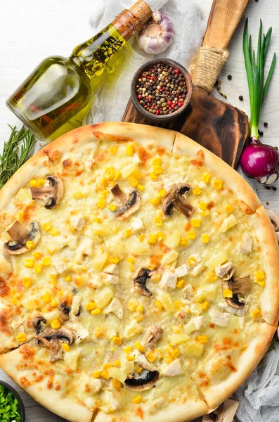 Hawaiian pizza with chicken, pineapple and mushrooms on the table. Rustic style. Top view.